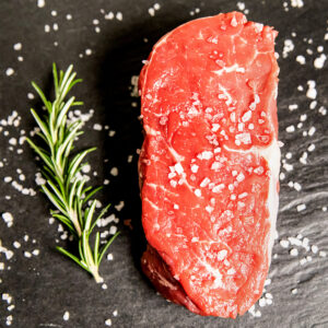 Rohes Rindersteak auf schwarzem Brett mit Rosmarin