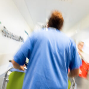Pfleger läuft dynamisch durch den Krankenhausflur.