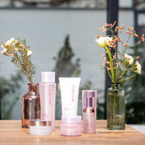 Produktfoto von Kosmetikprodukten auf Tisch mit Blumen