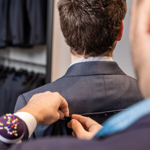 Person näht Anzug am Kragen – Business-Symbolbild