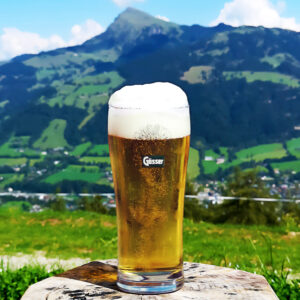 las Bier mit Schaum vor Alpenpanorama in Österreich