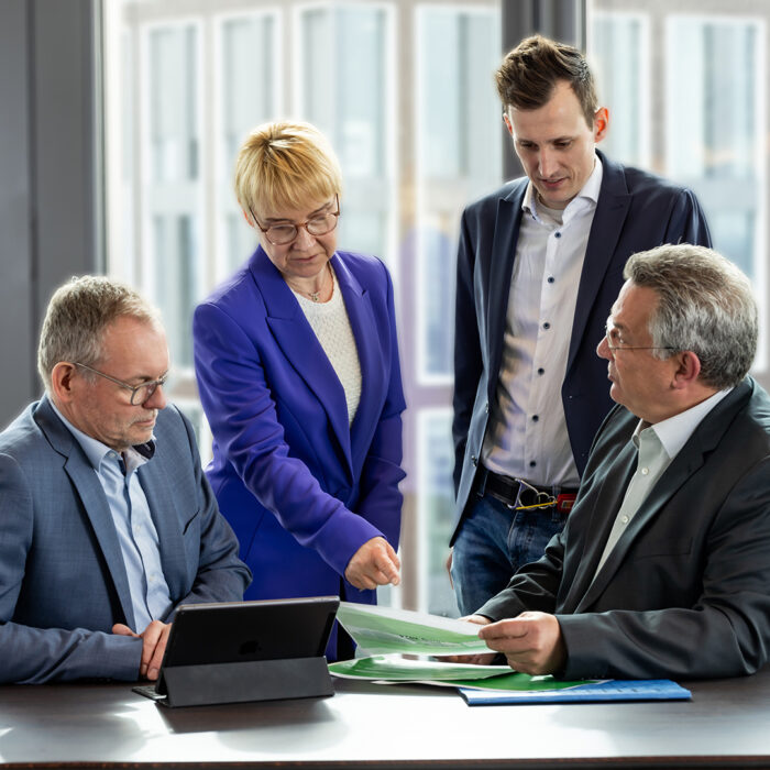 Gruppe von Mitarbeitern im Teammeeting an einem Tisch – Unternehmensfotografie
