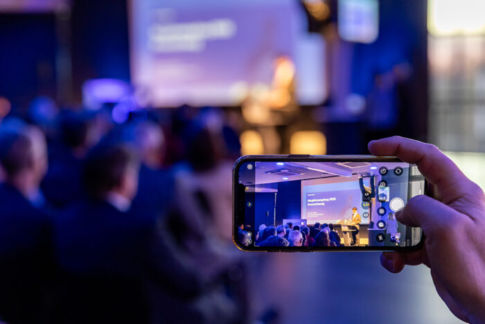 Neujahrsempfang der Deutschen Bank in Braunschweig mit Gästen aus Frankfurt. Ein Handy wird hochgehalten, dass die Bühne fotografiert